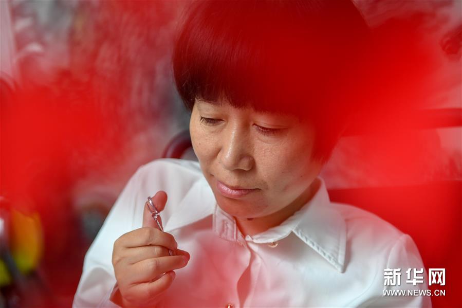 6月29日，华丽在创作剪纸作品。华丽是吉林省吉林市人，满族，自幼因病落下残疾。凭借坚强的意志和勤奋的努力，她在家人的帮助下自学非遗满族剪纸。虽然行动不便，但华丽的双手十分灵巧，一张普通的红纸经过她的艺术加工，就变成了一幅表现满族民俗文化的剪纸作品。在她的带动下，丈夫宋丽朋、儿子宋晔也加入到剪纸艺术的创作中。 为传承发展剪纸艺术，华丽和丈夫在吉林市创办了剪纸工作室，并免费为残疾人朋友提供剪纸培训。新华社记者 张楠 摄