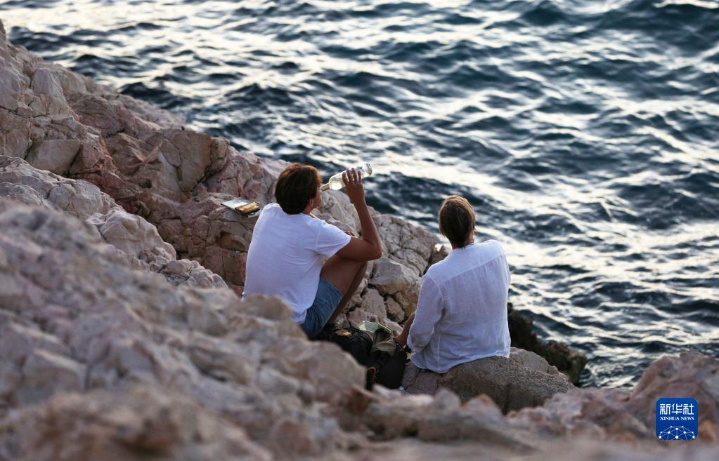 9月4日，人们在法国马赛海边礁石上休闲。新华社记者 高静 摄