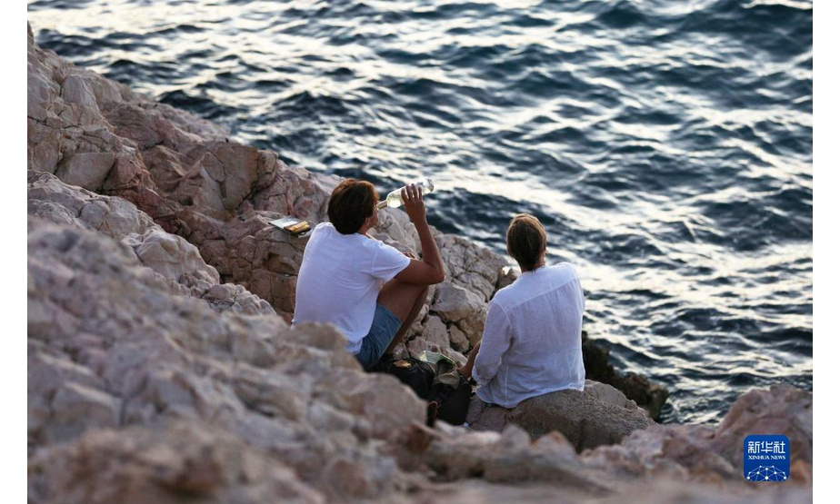 9月4日，人们在法国马赛海边礁石上休闲。新华社记者 高静 摄