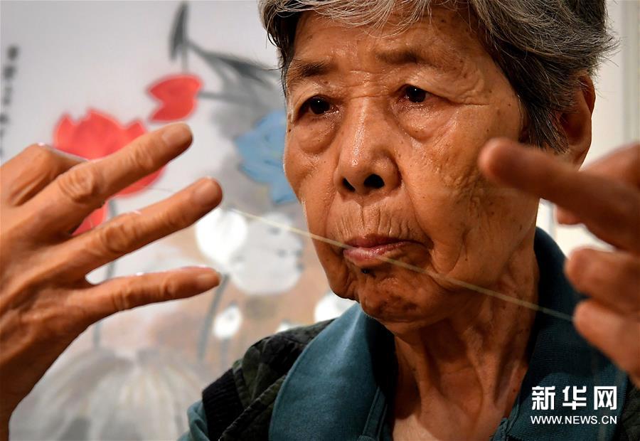 在开封市素花宋绣工艺有限公司的展示馆里，王素花在劈线（7月30日摄）。新华社记者李安摄