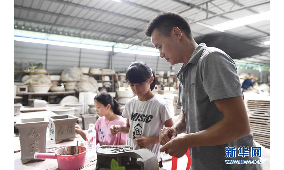 赵勇（右）在自己创办的陶瓷制品加工厂内教女儿（中）给陶瓷花瓶贴花（8月11日摄）。  新华社记者 曹祎铭 摄