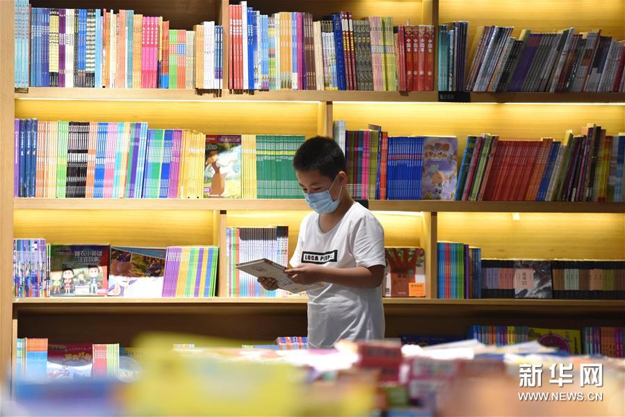 7月5日，一名小朋友在河北省定州市新华书店挑选图书。新华社记者 朱旭东 摄