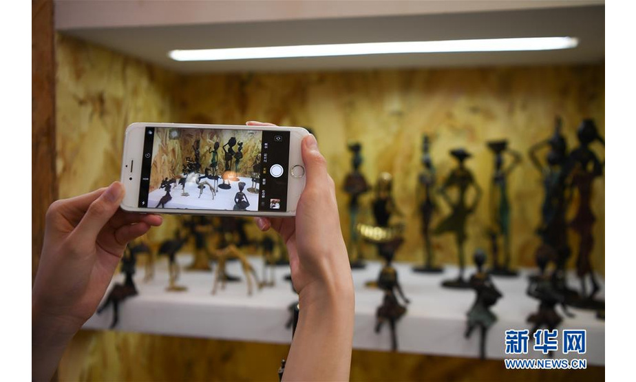 　6月28日，参观者在马里共和国展位拍摄手工铜塑。  新华社记者 薛宇舸 摄