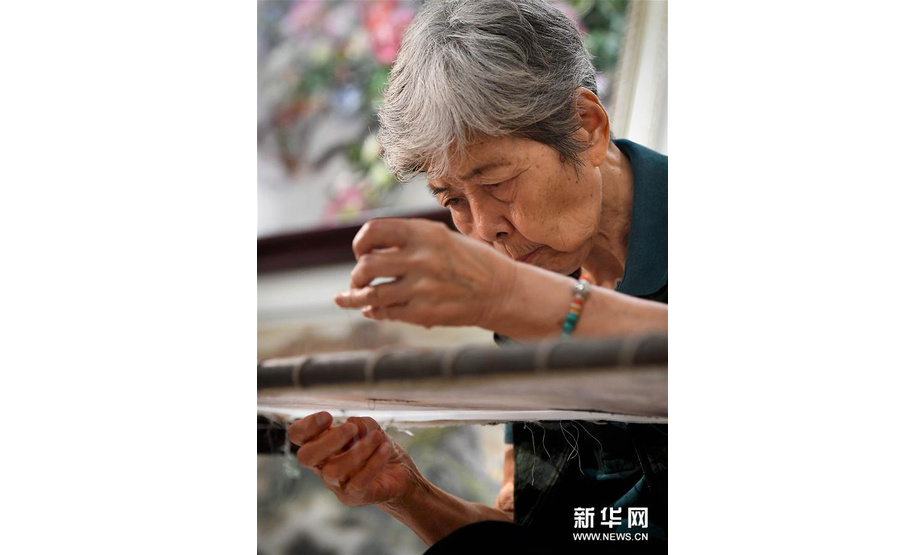 在开封市素花宋绣工艺有限公司的展示馆里，王素花在刺绣（7月30日摄）。新华社记者李安摄