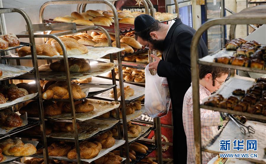 9月5日，在耶路撒冷的犹太社区，一名正统犹太教徒（左）选购“沙拉”面包，迎接即将到来的安息日。新华社发（吉尔·科恩·马根 摄）