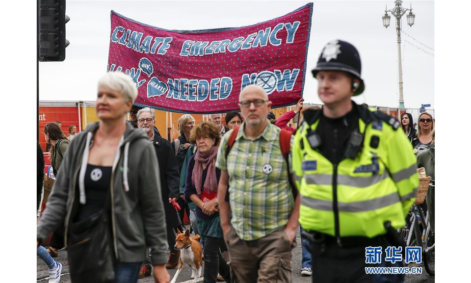 9月22日，在英国布莱顿，人们手持标语参加气候变化游行。 当日，民众在英国布莱顿举行游行活动，呼吁社会各界应对气候变化。 新华社记者韩岩摄