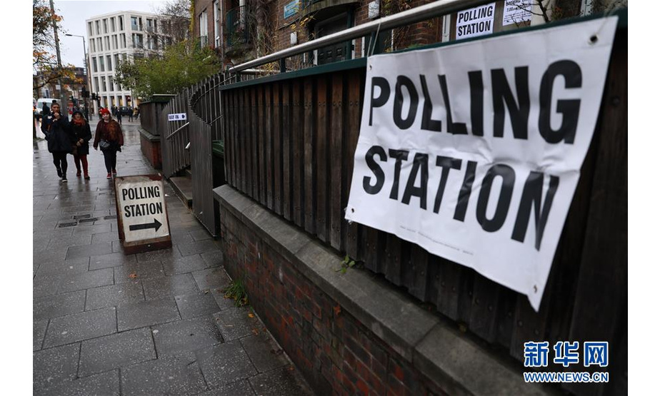 12月12日，在英国伦敦，行人经过一处投票站。 英国议会下院选举投票于当地时间12日7时开始。此次选举被称为“决定命运”的一次选举。 新华社发（蒂姆·爱尔兰 摄）