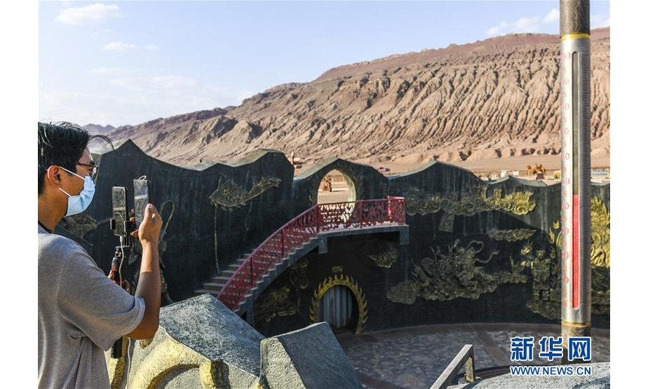 9月21日，一名来自广东的网络主播在位于新疆吐鲁番的火焰山景区进行网络直播。 暑气褪去，新疆吐鲁番迎来旅游黄金期，游客尽享当地独特风情。 新华社记者 王菲 摄