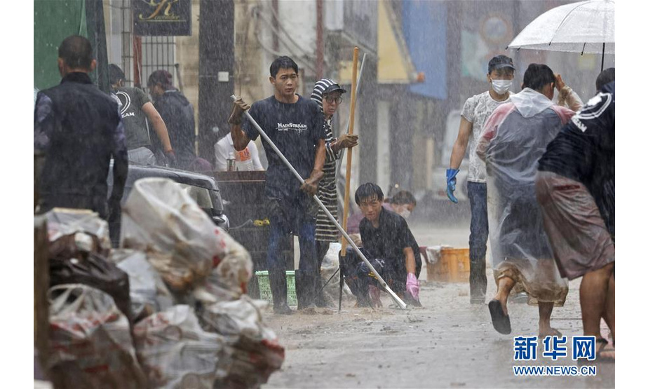 7月7日，日本熊本县人吉市居民在大雨中清理街道。 受停滞的梅雨锋面影响，日本九州地区北部7日继续遭遇强降雨天气。迄今，九州因暴雨引发的洪水泛滥、山体滑坡造成的死亡人数升至55人，另有13人失踪。 新华社/共同社