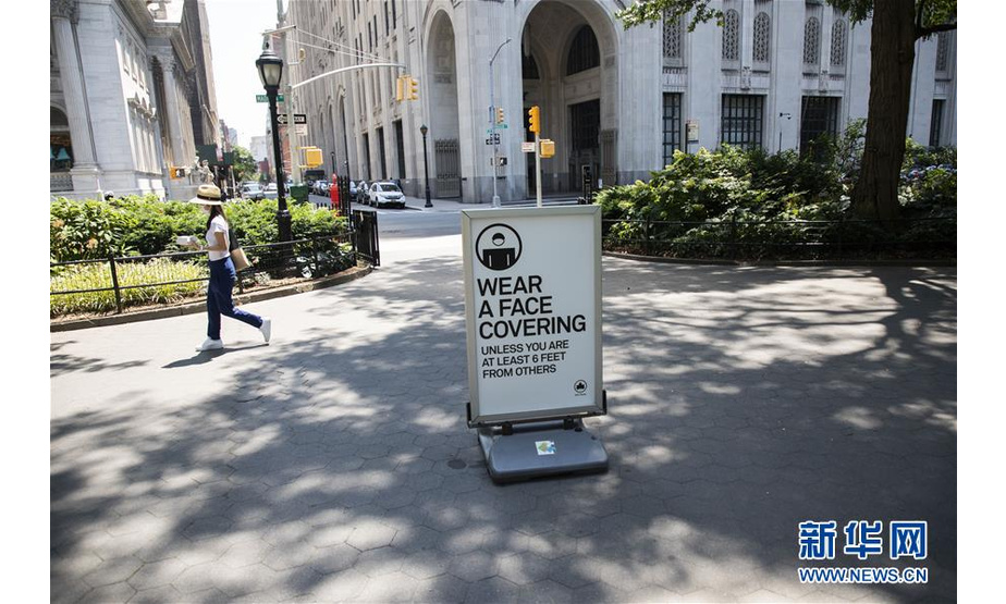 7月6日，行人走过美国纽约一处提醒人们佩戴口罩的标牌。新华社记者 王迎 摄
