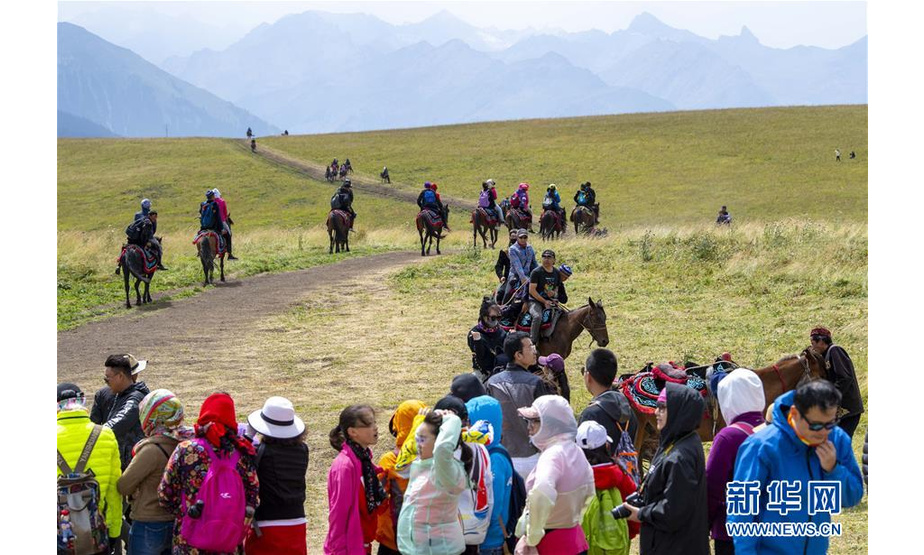 8月14日，游客在喀拉峻草原上体验骑马。 喀拉峻草原位于新疆伊犁河谷的特克斯县境内，山峦连绵起伏，线条柔美，层次分明，犹如一幅大气磅礴的天然画卷。 新华社记者 胡虎虎 摄