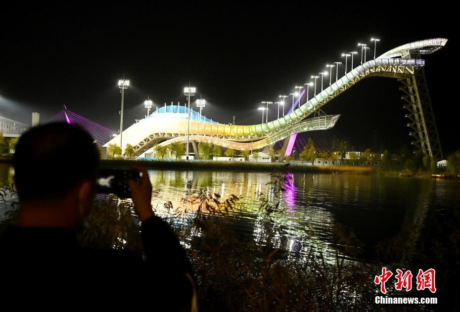 10月26日晚，北京首钢滑雪大跳台流光溢彩，吸引市民拍照。 中新社记者 张兴龙 摄