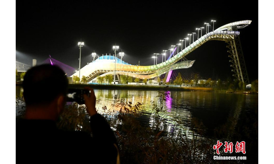10月26日晚，北京首钢滑雪大跳台流光溢彩，吸引市民拍照。 中新社记者 张兴龙 摄