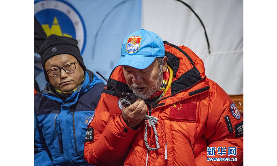 5月27日，在海拔5200米的珠峰大本营，2020珠峰高程测量登山队总指挥、国家体育总局登山运动管理中心副主任王勇峰（右）正在和位于海拔8300米突击营地的测量登山队队员通话。 当日2时10分许，2020珠峰高程测量登山队8名队员陆续从海拔8300米的珠峰突击营地启程向顶峰进发。 新华社记者 普布扎西 摄