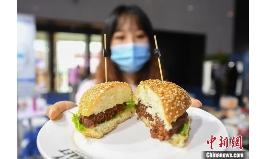 近日，在举办于浙江杭州的FBIF2020食品饮料创新论坛展览中，多款由黄豆蛋白、大豆蛋白等制作的人造植物肉食品亮相，吸引民众参观、品尝。图为:工作人员展示利用人造植物肉搭配制作的汉堡。 王刚 摄