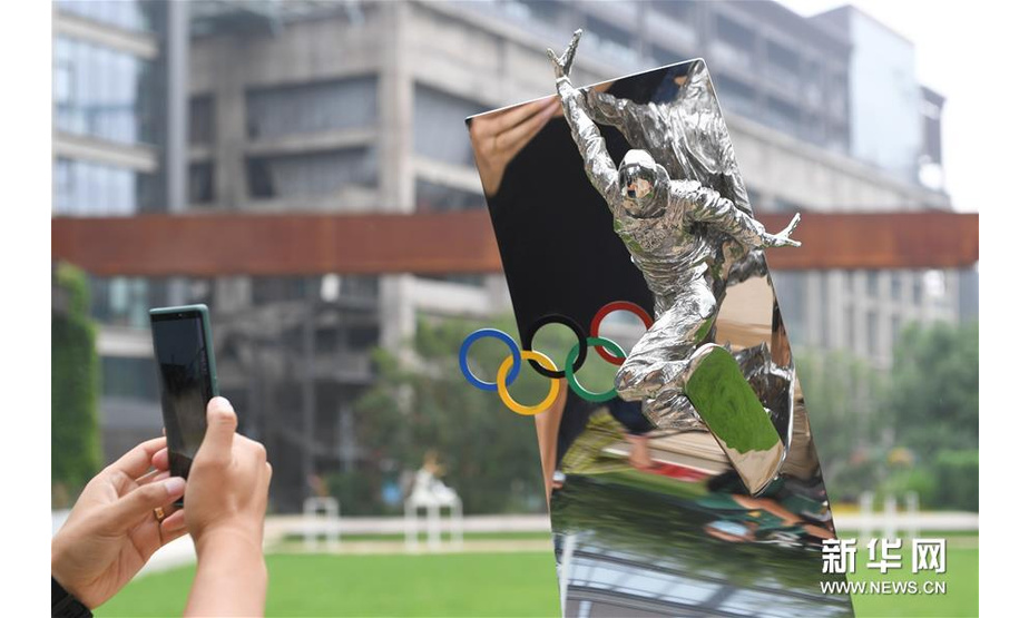 7月13日，参观者在拍摄展出的雕塑作品《单板滑雪——高飞》。 新华社记者鞠焕宗摄