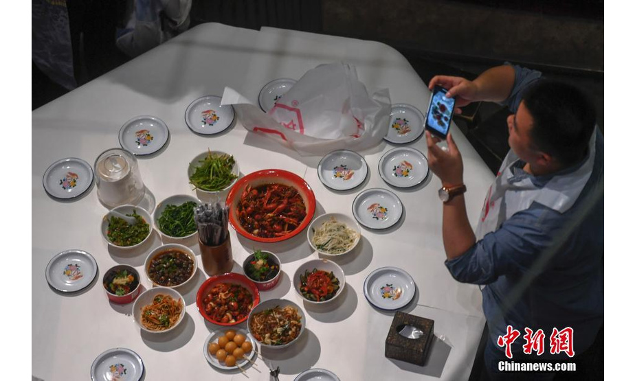 6月13日，一位食客正在拍摄菜品。该餐厅拥有近5000平方米的超大空间，融合了老长沙的人文情怀和特色餐饮的新创意，完全还原了上世纪八十年代老长沙的风貌，受到了众多都市人的热捧。中新社记者 杨华峰 摄