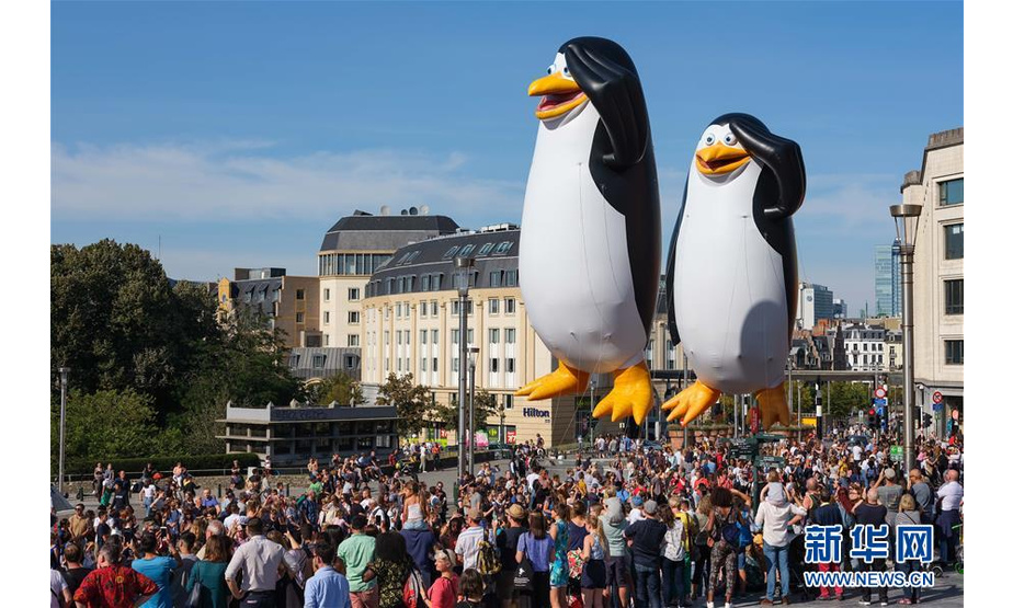 9月15日，人们在比利时首都布鲁塞尔观看卡通气球大巡游。 当日，布鲁塞尔举行第十届布鲁塞尔漫画节卡通气球大巡游，形态各异的卡通气球从街头巷尾穿行而过，吸引大批市民和游客。 新华社记者 张铖 摄
