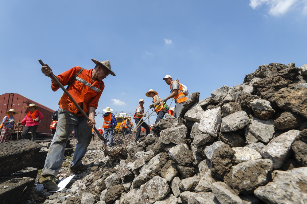 8月4日，鹰潭工务机械段的工作人员对铁轨上的石砟进行清理。