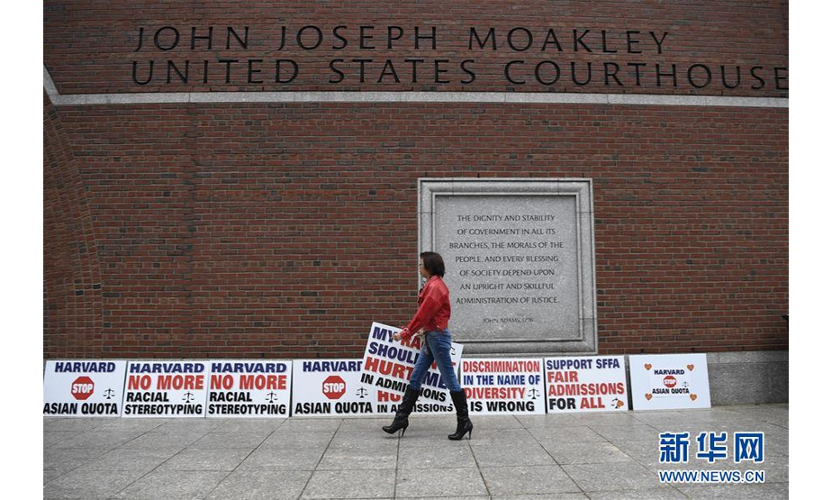 10月15日，在美国马萨诸塞州波士顿，一名反对哈佛大学歧视亚裔学生的抗议者在美国联邦地区法院前手拿标语牌。  新华社记者刘杰摄