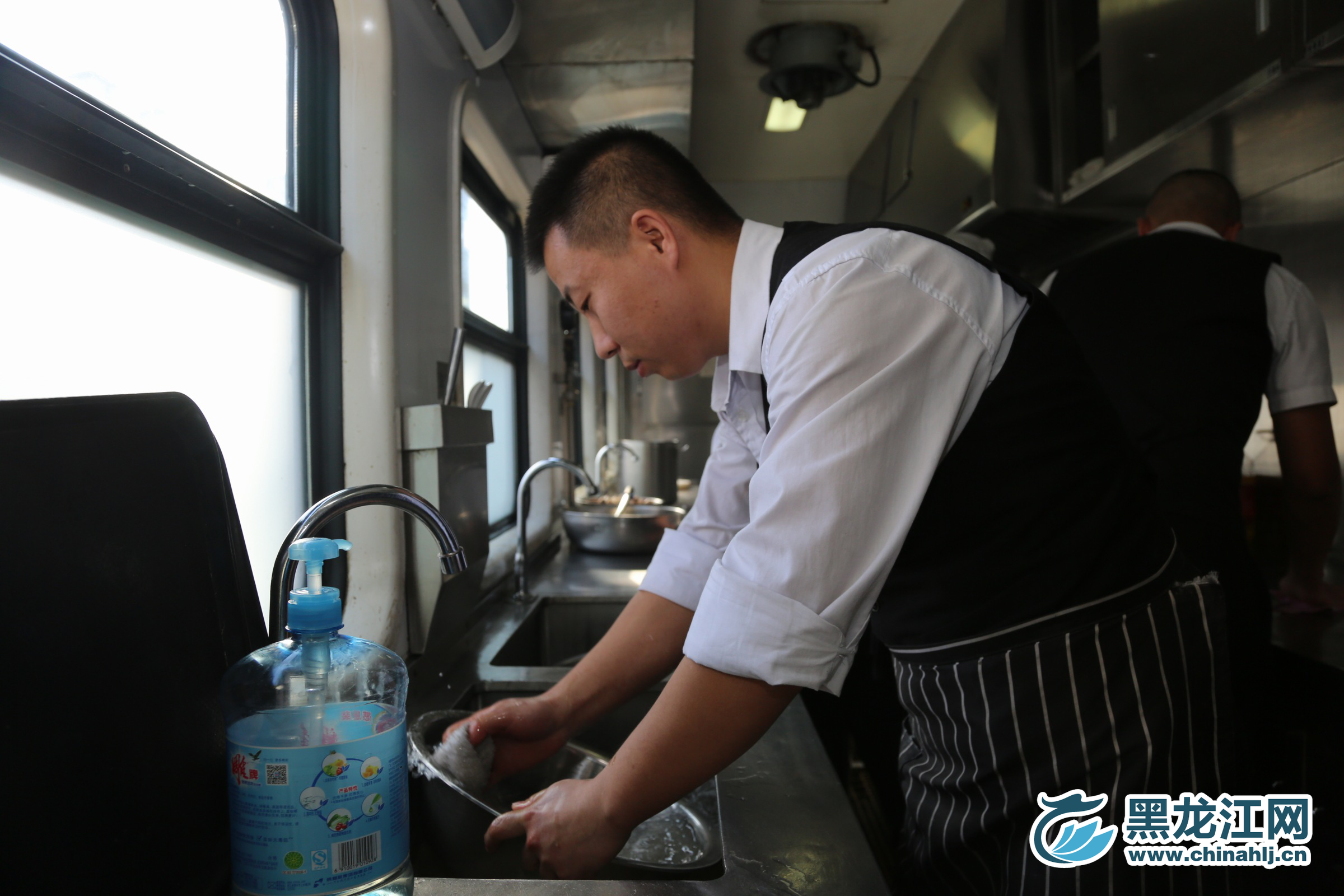 黑龙江网2月1日讯 （记者 石启立）黑龙江网记者来到Z114次列车厨房，看看师傅们是如何为大家准备丰盛饭菜的。图为师傅在清洗餐具。石启立 摄