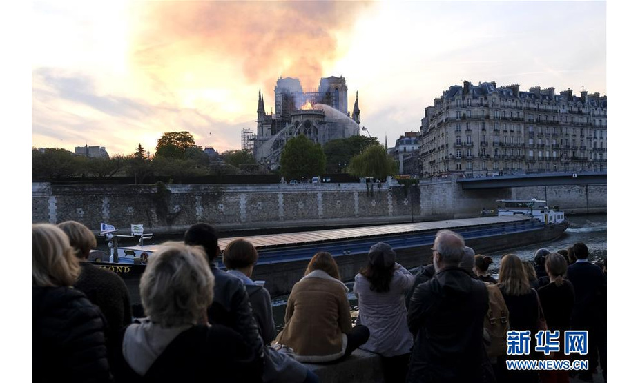 4月15日，在法国巴黎，人们围观着火的巴黎圣母院。新华社发（亚历山大·卡曼摄）