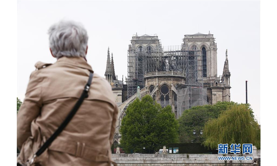 4月16日，在法国巴黎，一名老妇人在塞纳河畔望着“受伤”的巴黎圣母院。新华社记者 高静 摄