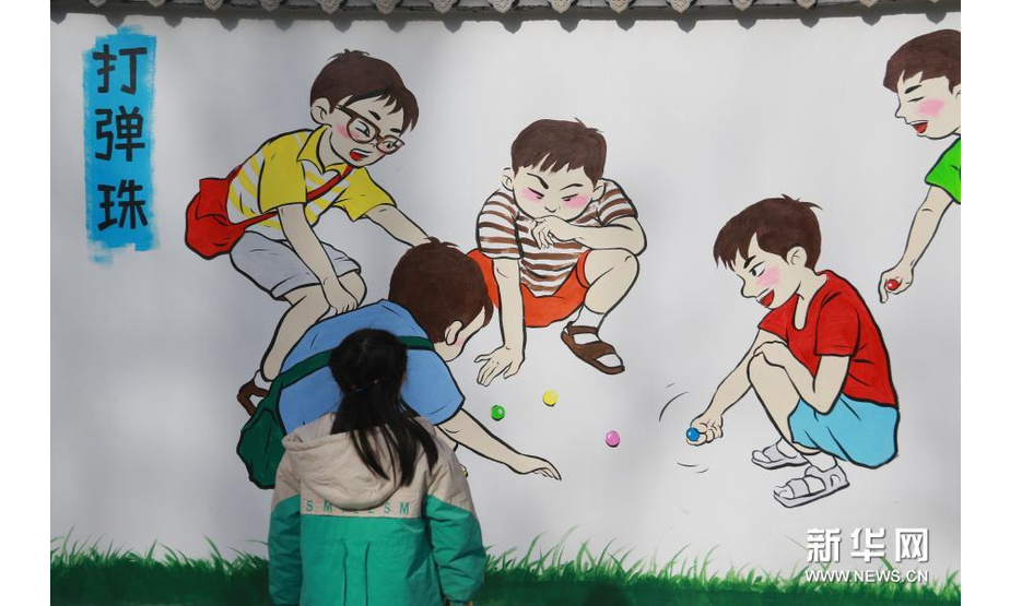 12月5日，一名小朋友在敦煌市沙州镇南街社区观看文化墙。新华社发（张晓亮 摄）