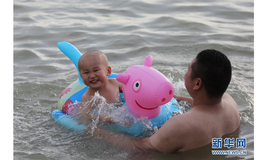 8月2日，家长带着孩子在江苏省淮安市洪泽区渔人湾浴场游玩。 新华社发（万震 摄）