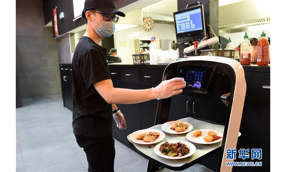 5月28日，在奥地利维也纳一家亚洲餐厅内，服务员为机器人设置送餐桌号。 维也纳的一家亚洲餐厅于疫情期间重新营业后，更多利用机器人上菜，以减少服务员和顾客之间的非必要接触。 新华社记者 郭晨 摄