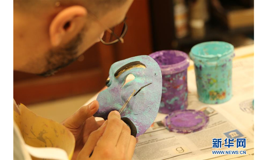 2月16日，在意大利威尼斯，一位游客在面具工坊绘制自己的威尼斯面具。 一年一度的威尼斯狂欢节正在意大利北部水城威尼斯举行，大街小巷挤满了着华丽服饰、戴精美面具的狂欢者，人们尽情享受节日的欢乐气氛。面具是威尼斯狂欢节的最大特色，也最令游客感兴趣。 新华社发（黄万晴 摄）