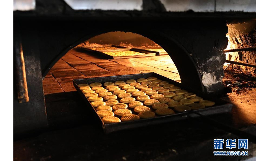 这是8月21日在伊拉克巴格达一家面包店拍摄的烤制中的“克莱佳”。新华社发（哈利勒·达伍德摄）