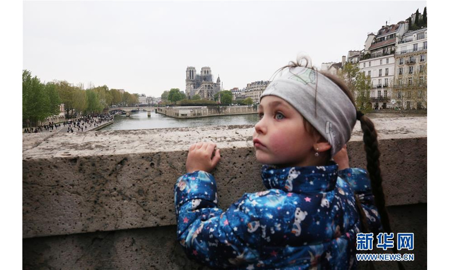 4月16日，在法国巴黎，一名小女孩在桥上看望“受伤”的巴黎圣母院。新华社记者 高静 摄