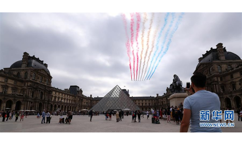 7月14日，在法国巴黎举行的国庆阅兵仪式上，“法兰西巡逻兵”飞行表演队飞过卢浮宫金字塔广场上空。 当日，法国在首都巴黎举行国庆阅兵仪式。 新华社记者 高静 摄