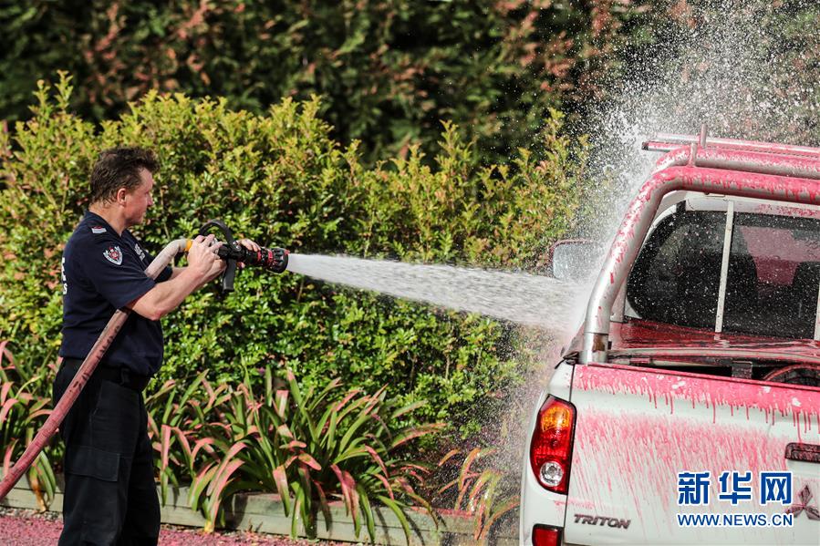 11月12日，在澳大利亚悉尼附近的南塔勒马拉，消防员在灭火后清洗车辆上的灭火剂。 近日，澳大利亚东部林火继续肆虐，大悉尼地区面临“灾难级”林火威胁。悉尼所在的新南威尔士州州长贝雷吉克利安11日宣布该州进入为期7天的紧急状态。12日，最近的起火点已逼近悉尼城区，林火造成城市上空被大量烟尘笼罩。 新华社记者 白雪飞 摄