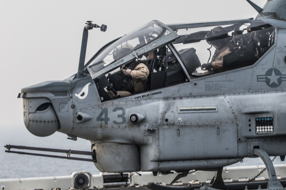 8月12日，美国海军两栖攻击舰“拳师”号（USS Boxer）通过了霍尔木兹海峡。为保障安全，“拳师”号上的多架AH-1Z“眼镜蛇”攻击直升机起飞待命。从照片中可以看到，一辆装甲车也开到了两栖攻击舰的甲板边缘处，美军士兵在车上保持戒备。