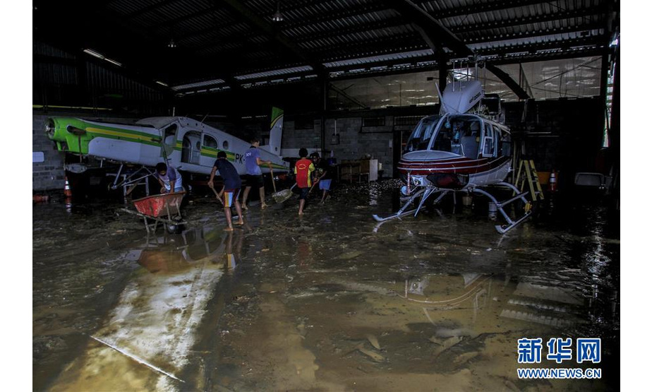 3月17日，在印度尼西亚巴布亚省森塔尼，人们在一个机库中清理洪水过后的污泥。印度尼西亚抗灾署17日说，印尼东部巴布亚省16日晚发生的洪涝灾害已导致42人死亡、21人受伤。新华社发