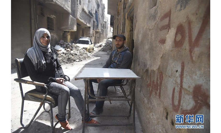 3月12日，在叙利亚大马士革东古塔地区，穆罕默德·谢哈德（右）和萨米拉·阿尤布夫妇坐在自家房屋旁。 新华社发（胡马姆·谢赫·阿里 摄）