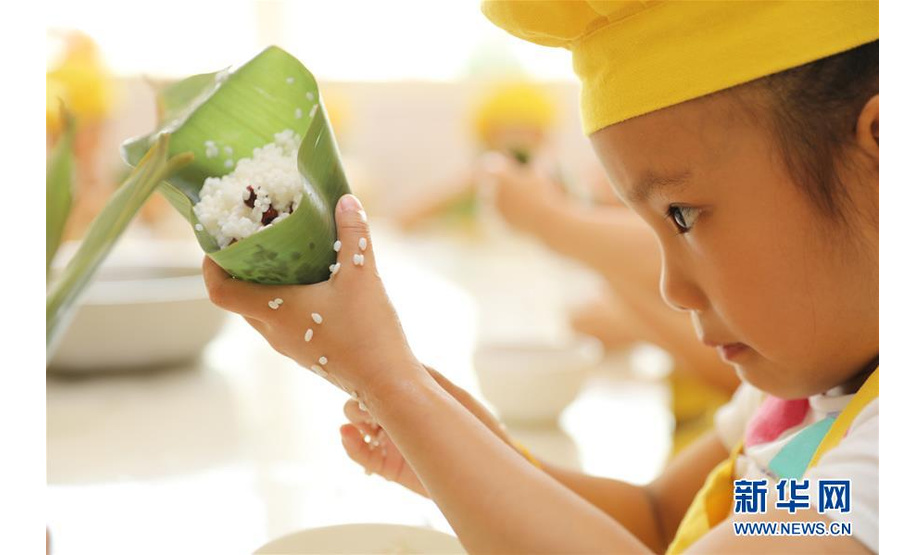 6月13日，在河北省石家庄市第一幼儿园，一名小朋友学习包粽子。端午节将至，人们开始包粽子、缝香囊，体验民俗活动，品味传统文化。 新华社发（张海强 摄）
