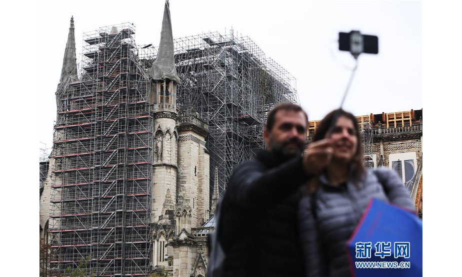 10月17日,在法国巴黎，人们在修缮中的巴黎圣母院前自拍留念。 据法国媒体15日报道，2016年企图袭击巴黎圣母院的5名涉恐人员14日被判处5年至30年徒刑。法国新闻广播电台报道说，5名涉恐人员均为女性，年龄为22岁至42岁，她们在2016年9月企图点燃一辆装载天然气罐的汽车，对法国著名景点巴黎圣母院发动袭击。警方最终挫败其恐怖袭击阴谋。 新华社记者高静摄