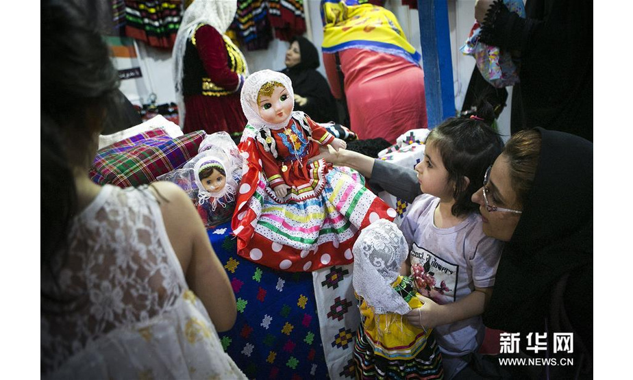 8月17日，在伊朗德黑兰，顾客在第四届德黑兰传统游牧文化展上挑选游牧民制作的娃娃。 新华社发（艾哈迈德·哈拉比萨斯摄）