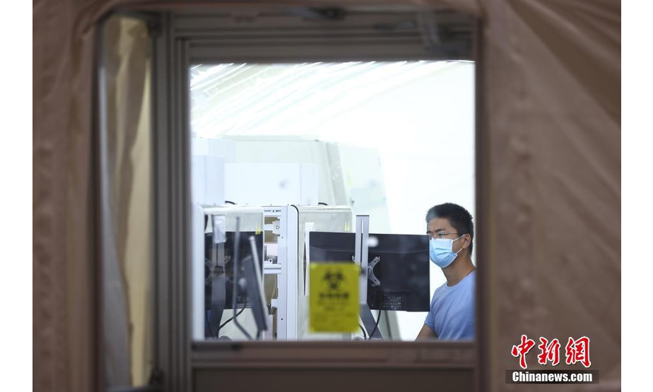 7月26日，南京“火眼”实验室正在南京国际博览中心加紧搭建，工作人员调试设备。实验室建造面积达8000平方米、配备12个硬气膜实验室和15个软气膜实验室，同时配备了全自动分杯处理系统、高通量自动化病毒核酸提取设备等，能够在快速提高检测效率的同时，降低检测人员感染的风险。该实验室全部建成后，若采用“10人混采”模式，单日核酸检测能力最高可达200万人份。