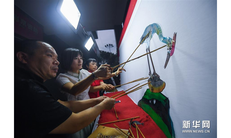 7月21日，“卫家班皮影戏”剧团的艺人们在和睦桥村的文化礼堂前为村民们上演传统皮影戏《鹬蚌相争 渔人得利》。新华社记者 徐昱 摄
