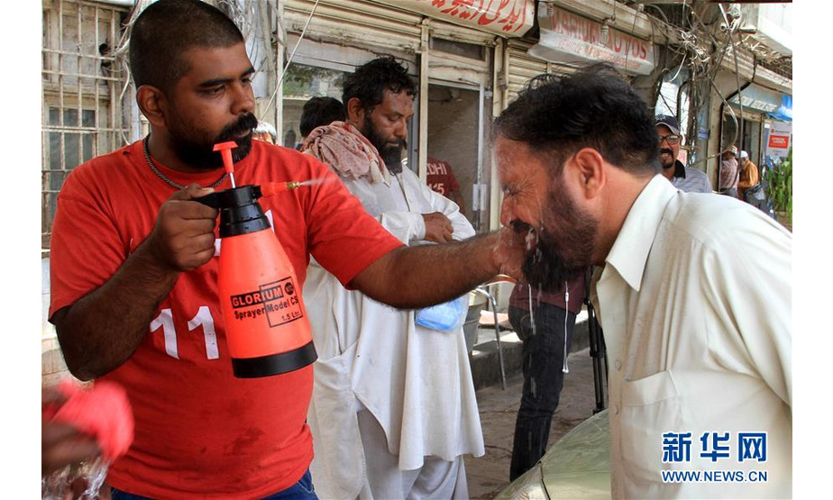 5月22日，在巴基斯坦卡拉奇，一名男子接受喷水降温。近日，巴基斯坦南部城市卡拉奇连遇高温天气，最高气温达44摄氏度，已造成至少65人死亡。新华社发