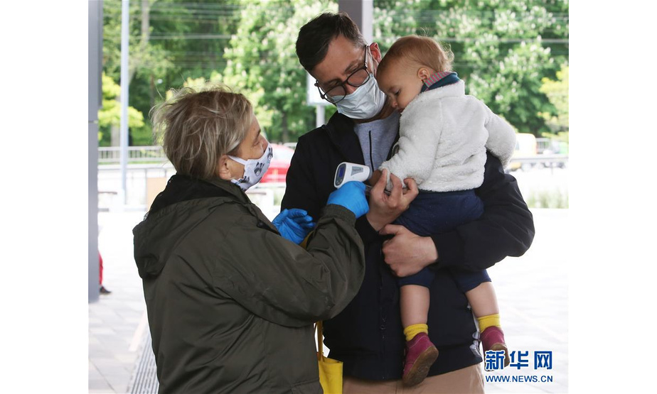 5月23日，在乌克兰基辅动物园，工作人员为准备入园的儿童检测体温。新华社发（谢尔盖·斯塔拉斯坚科摄）
