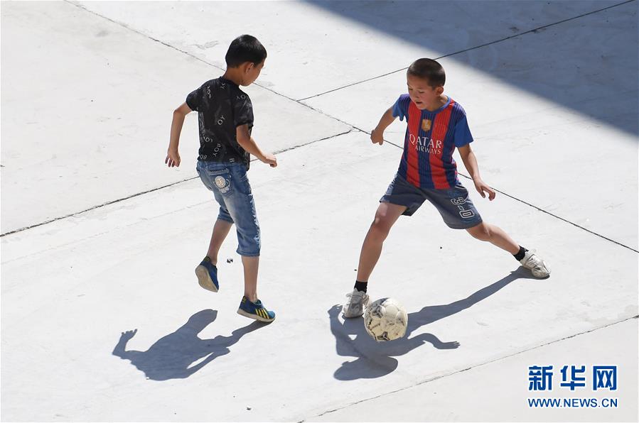 在新疆阿勒泰地区青河县阿格达拉镇，小朋友在新居前玩耍（8月9日摄）。 新华社记者 沙达提 摄