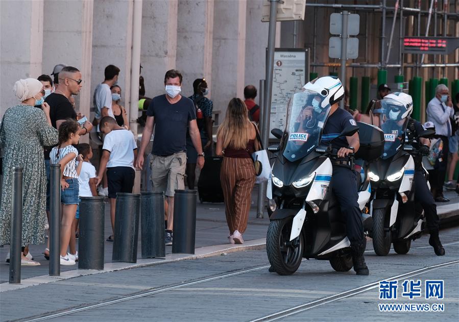 8月4日，在法国尼斯市中心，警察提醒行人佩戴口罩。 新华社发（塞尔日·阿乌齐摄）