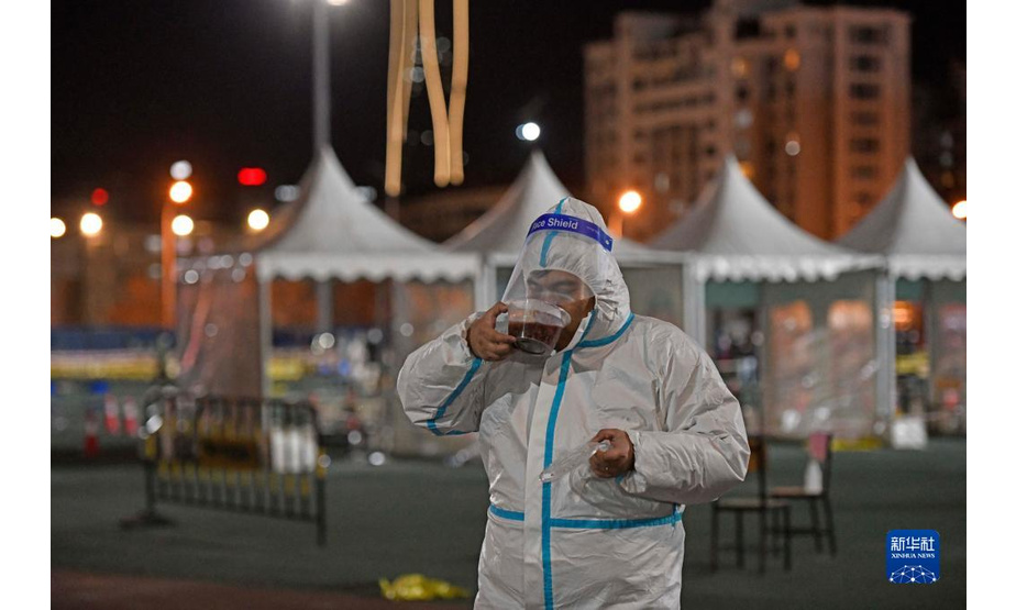 1月10日，在天津市滨海新区泰达第一体育场核酸检测点，工作人员在工作间隙品尝腊八粥。新华社记者 赵子硕 摄
