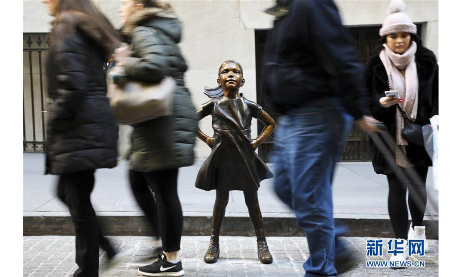 12月10日，在美国纽约，人们从纽约证券交易所前的“无畏女孩”铜像旁走过。  新华社记者 王迎 摄