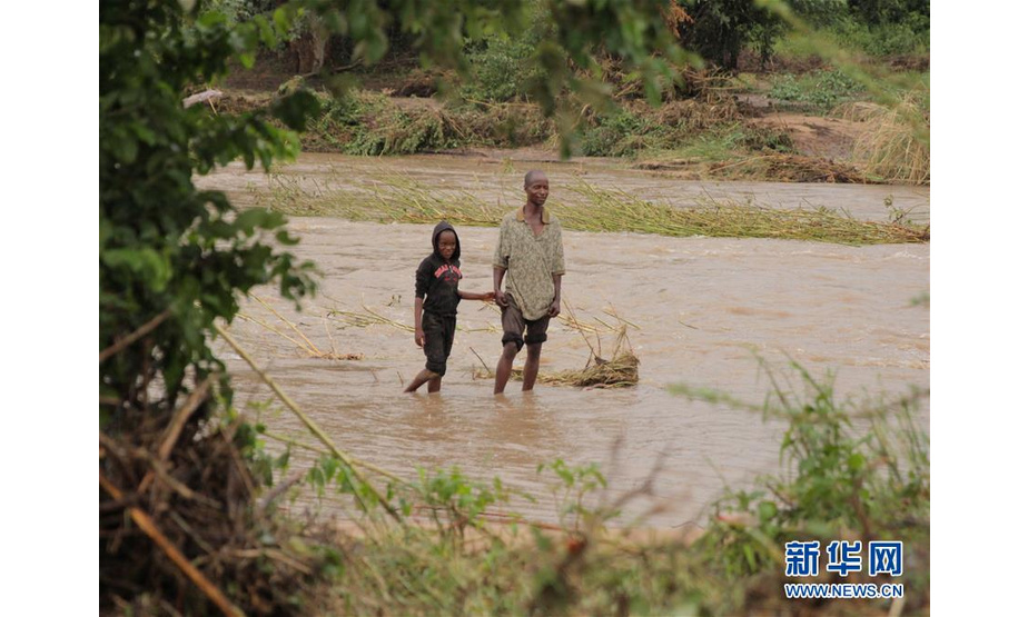 3月17日，在津巴布韦马尼卡兰省的奇马尼马尼，人们在涨水的河中穿行。 津巴布韦政府16日表示，15日晚开始袭击该国东部的强热带气旋“伊代”造成的死亡人数升至31人，另有数十人失踪。 新华社发（肖恩·朱萨摄）